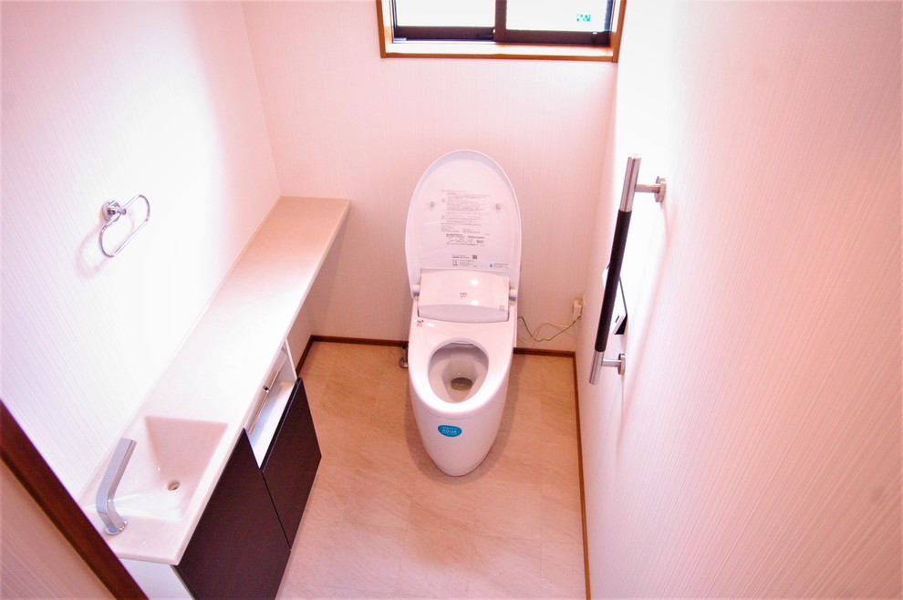 Réalisation d'un grand WC et toilettes asiatique avec des portes de placard marrons, WC à poser, un mur blanc, un plan de toilette en surface solide et un sol beige.