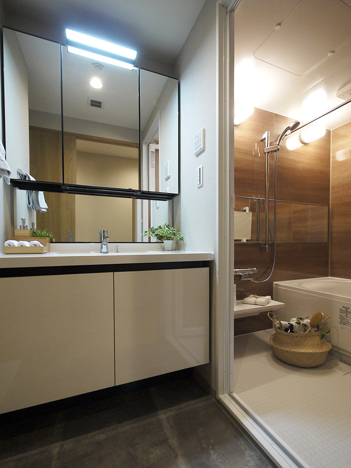 東京23区にあるモダンスタイルのおしゃれなトイレ・洗面所 (白いキャビネット、一体型トイレ	、茶色いタイル、グレーの壁、クッションフロア、グレーの床、白い洗面カウンター) の写真