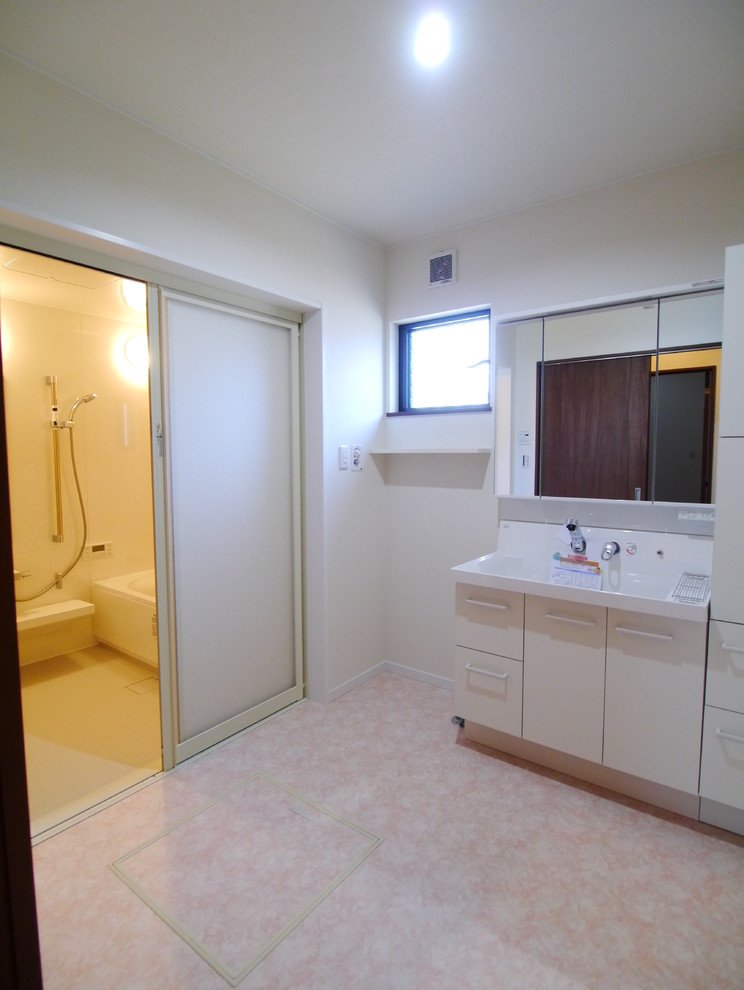 他の地域にあるトランジショナルスタイルのおしゃれなトイレ・洗面所 (白いキャビネット、白い壁、クッションフロア、ピンクの床) の写真