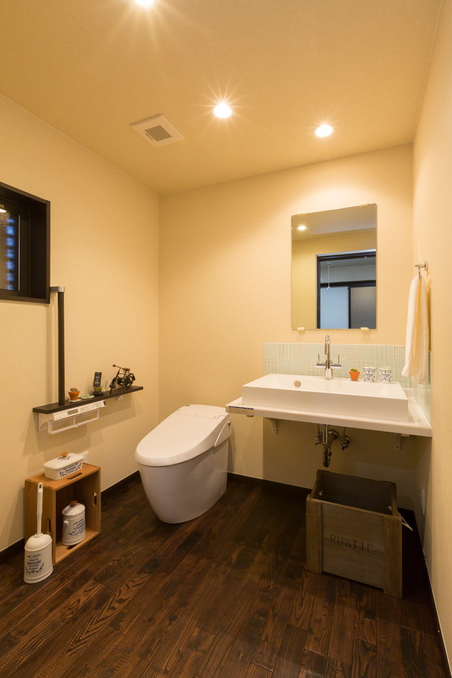 Imagen de aseo asiático con paredes beige, suelo de madera oscura, lavabo tipo consola y suelo marrón