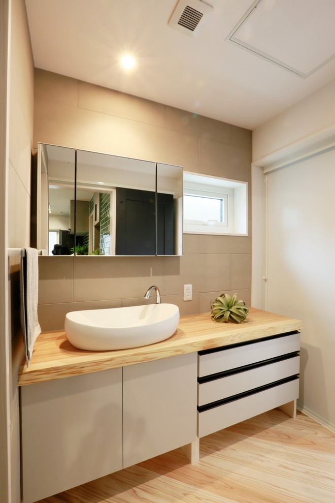 Immagine di un bagno di servizio design con ante lisce, ante grigie, pareti grigie, parquet chiaro, lavabo a bacinella, top in legno, pavimento beige e top beige