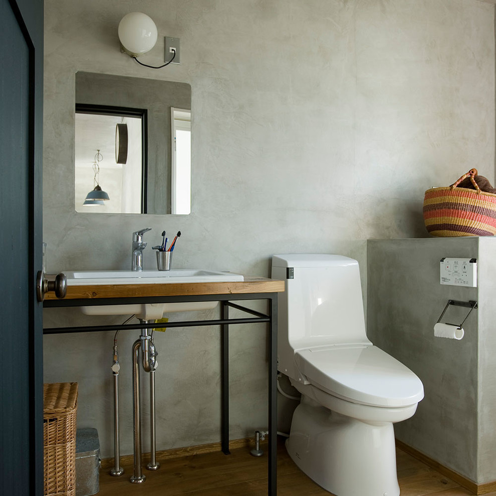 他の地域にあるインダストリアルスタイルのおしゃれなトイレ・洗面所 (グレーのタイル、グレーの壁、無垢フローリング、ベッセル式洗面器、茶色い床) の写真