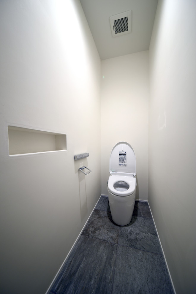 Идея дизайна: большой туалет в стиле модернизм с унитазом-моноблоком, серой плиткой, керамогранитной плиткой, белыми стенами, полом из керамогранита и серым полом