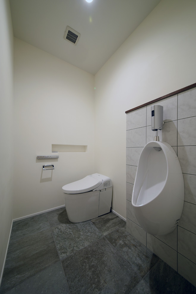 На фото: большой туалет в стиле модернизм с писсуаром, серой плиткой, керамогранитной плиткой, белыми стенами, полом из керамогранита и серым полом