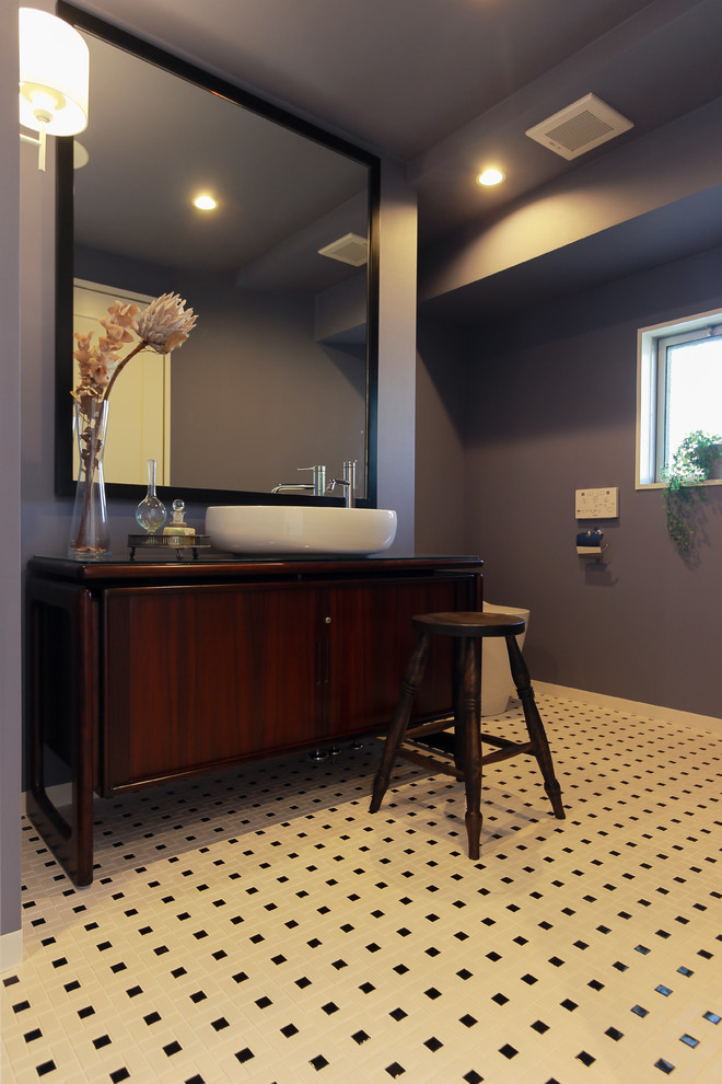 Exemple d'un WC et toilettes rétro avec des portes de placard marrons, un mur gris, un placard à porte plane, une vasque, un plan de toilette en bois, un sol multicolore et un plan de toilette marron.