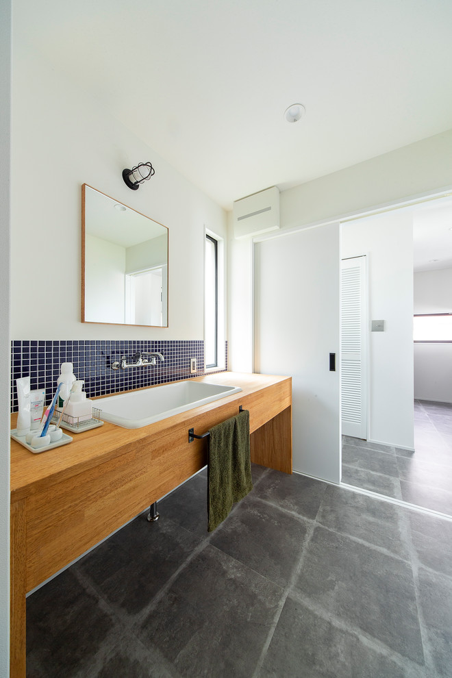 На фото: туалет среднего размера в стиле лофт с открытыми фасадами, фасадами цвета дерева среднего тона, синей плиткой и коричневой столешницей с