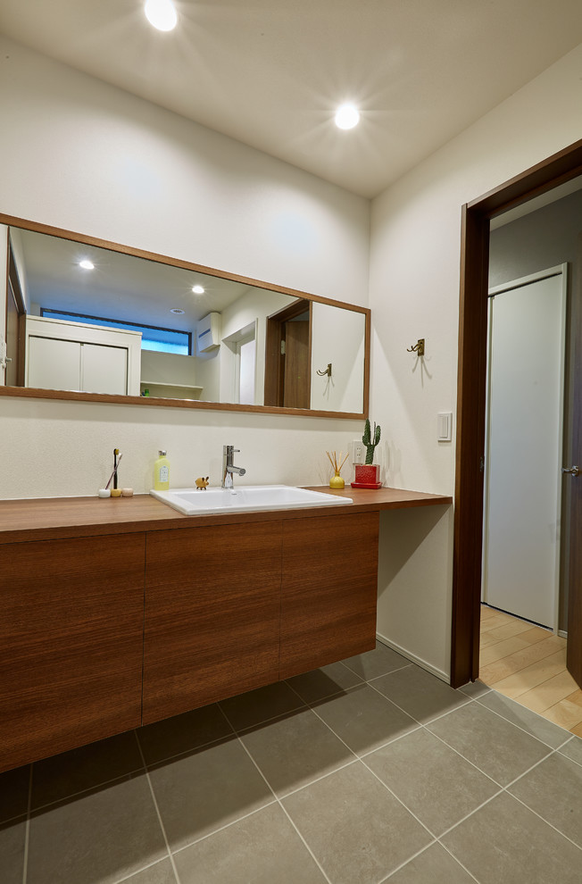 Idées déco pour un WC et toilettes contemporain en bois brun avec un mur blanc, un plan de toilette en bois et un sol gris.