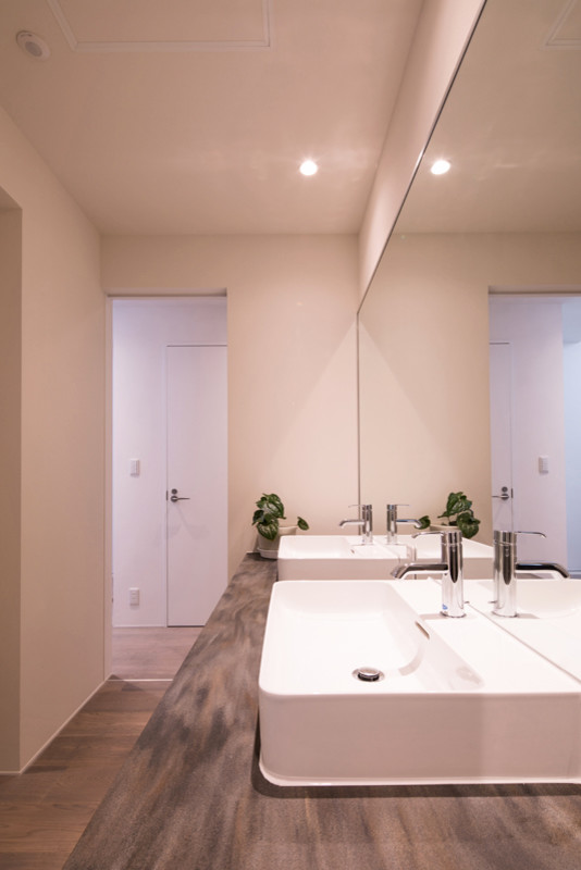 Foto på ett funkis vit toalett, med ljust trägolv, ett fristående handfat, bänkskiva i akrylsten och beiget golv