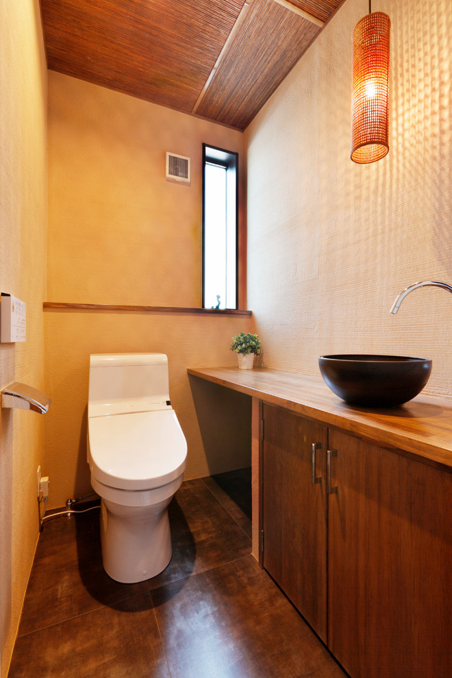 他の地域にある和風のおしゃれなトイレ・洗面所 (中間色木目調キャビネット、一体型トイレ	、ベージュの壁、木製洗面台、茶色い床、ブラウンの洗面カウンター) の写真