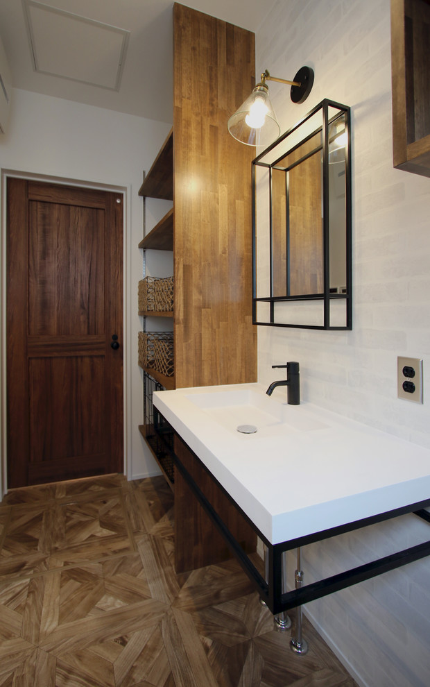 Inredning av ett asiatiskt toalett, med öppna hyllor, vit kakel, porslinskakel, vita väggar, vinylgolv, ett integrerad handfat, bänkskiva i akrylsten och brunt golv