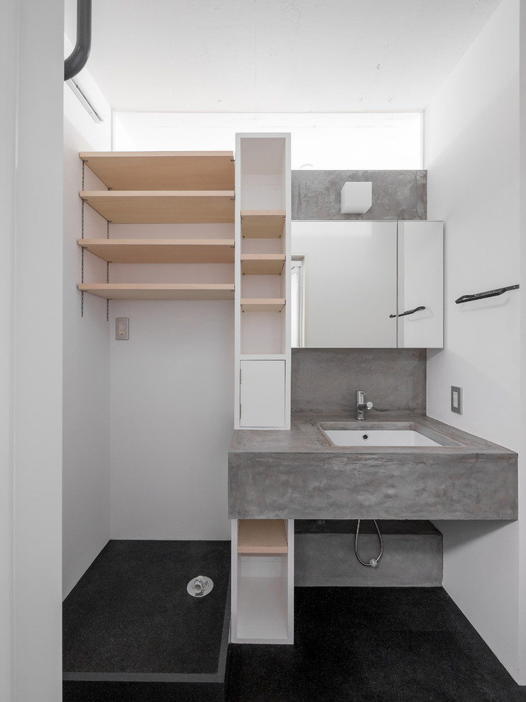 На фото: туалет в современном стиле с серой плиткой, белыми стенами, полом из линолеума, врезной раковиной, столешницей из бетона и черным полом