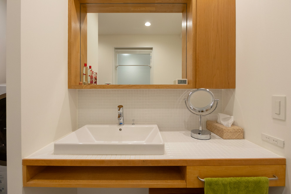 Immagine di un bagno di servizio design con piastrelle bianche, piastrelle in gres porcellanato, top piastrellato, pavimento grigio, top bianco e pareti bianche
