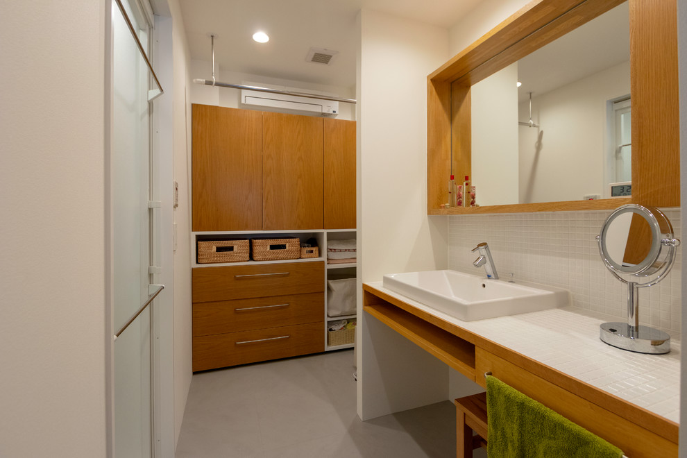 東京23区にあるコンテンポラリースタイルのおしゃれなトイレ・洗面所 (白いタイル、磁器タイル、タイルの洗面台、グレーの床、白い洗面カウンター、白い壁) の写真