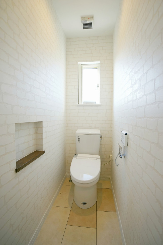 На фото: маленький туалет в скандинавском стиле с унитазом-моноблоком, бежевым полом, потолком с обоями, белыми стенами и полом из терракотовой плитки для на участке и в саду