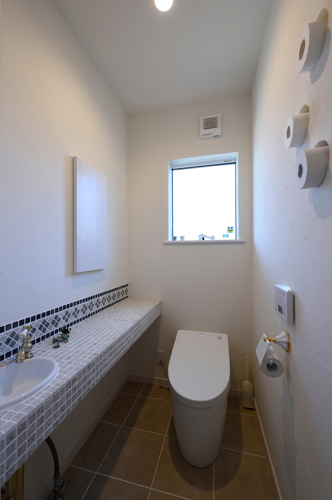 他の地域にある小さな地中海スタイルのおしゃれなトイレ・洗面所 (白い壁、オーバーカウンターシンク、ベージュの床) の写真