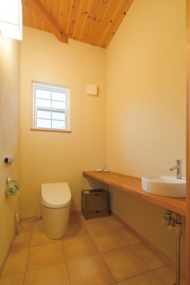 Идея дизайна: туалет в восточном стиле с унитазом-моноблоком, бежевыми стенами, полом из терракотовой плитки и бежевым полом