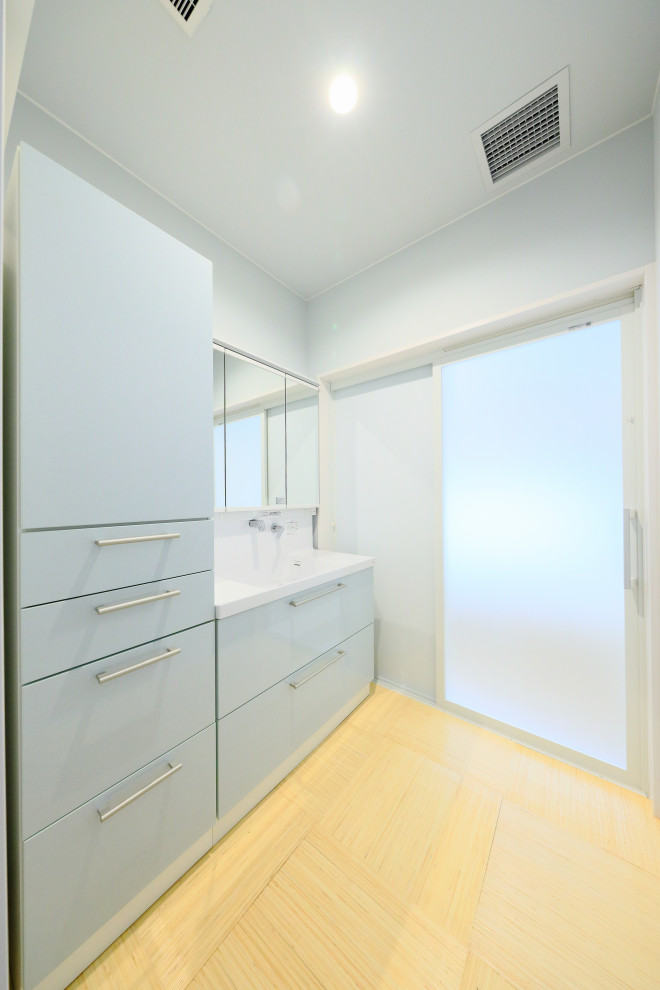 Immagine di un bagno di servizio classico di medie dimensioni con ante blu, top in superficie solida, top bianco e mobile bagno incassato