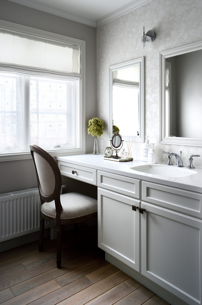 Exempel på ett klassiskt toalett, med grå skåp, mörkt trägolv, ett nedsänkt handfat, brunt golv och grå väggar