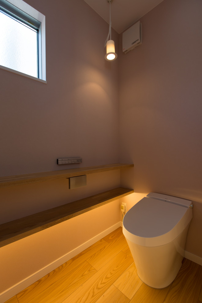 На фото: туалет среднего размера в скандинавском стиле с унитазом-моноблоком, розовыми стенами, паркетным полом среднего тона, бежевым полом, подвесной тумбой, потолком с обоями и обоями на стенах