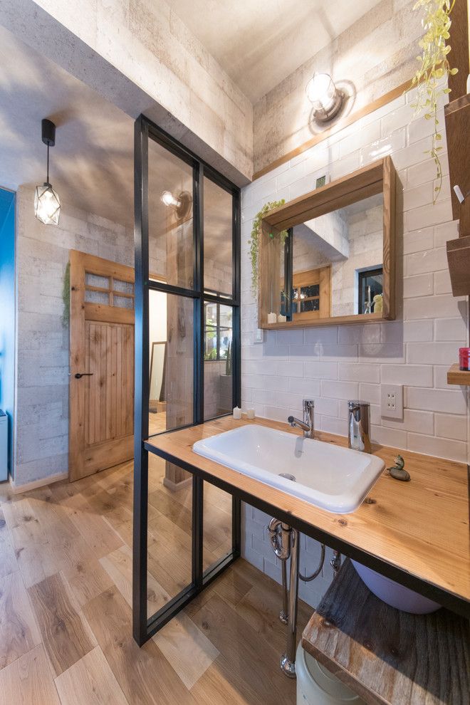 東京都下にある高級なインダストリアルスタイルのおしゃれなトイレ・洗面所 (オープンシェルフ、濃色木目調キャビネット、白いタイル、磁器タイル、青い壁、磁器タイルの床、グレーの床、ブラウンの洗面カウンター) の写真