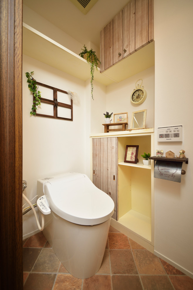 На фото: туалет в скандинавском стиле с плоскими фасадами, искусственно-состаренными фасадами, белыми стенами, полом из терракотовой плитки и коричневым полом с