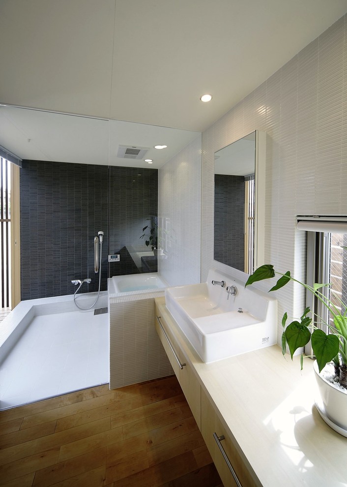 Idéer för att renovera ett funkis beige beige toalett, med släta luckor, beige skåp, vita väggar, mellanmörkt trägolv, ett fristående handfat, träbänkskiva och brunt golv