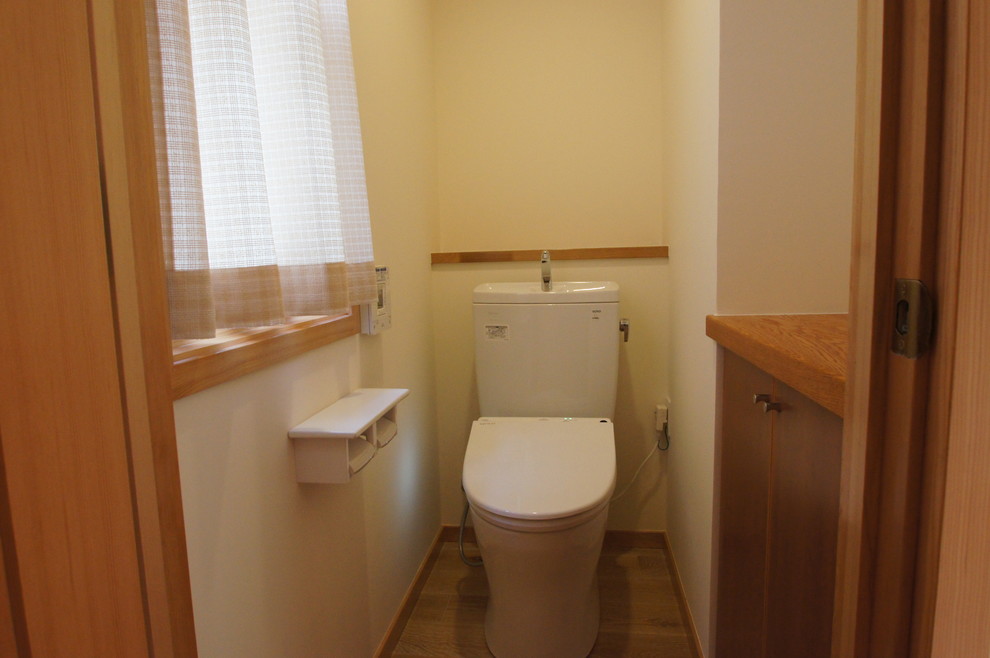 Aménagement d'un WC et toilettes campagne en bois foncé avec un placard à porte plane, un mur blanc, un sol en bois brun et un sol marron.