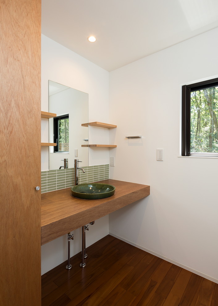 東京都下にあるコンテンポラリースタイルのおしゃれなトイレ・洗面所 (白い壁、無垢フローリング、ベッセル式洗面器、木製洗面台、茶色い床、ブラウンの洗面カウンター) の写真