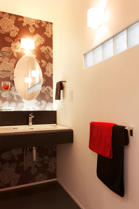 Foto di un piccolo bagno di servizio moderno con piastrelle nere, piastrelle a mosaico, pareti multicolore, pavimento in vinile, lavabo sottopiano, top in laminato, pavimento nero e top nero