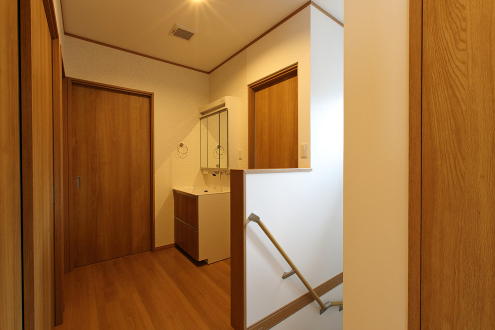 Example of a mid-sized zen plywood floor and brown floor powder room design in Other with white walls and an integrated sink