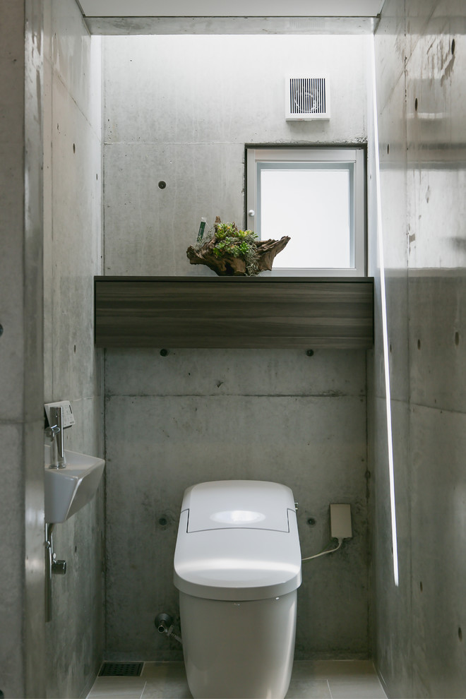 На фото: туалет в восточном стиле с серыми стенами, подвесной раковиной и серым полом с