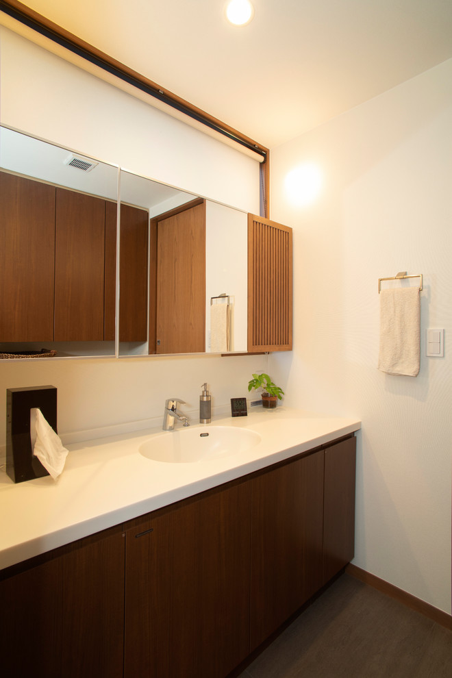 他の地域にあるミッドセンチュリースタイルのおしゃれなトイレ・洗面所 (フラットパネル扉のキャビネット、中間色木目調キャビネット、白い壁、一体型シンク、グレーの床) の写真