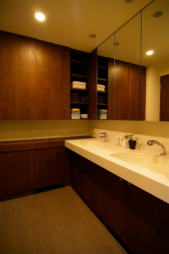 Cette photo montre un WC et toilettes rétro avec des portes de placard marrons, un carrelage marron, des carreaux de porcelaine, un mur blanc, un sol en bois brun, un plan de toilette en carrelage, un sol marron et un plan de toilette marron.