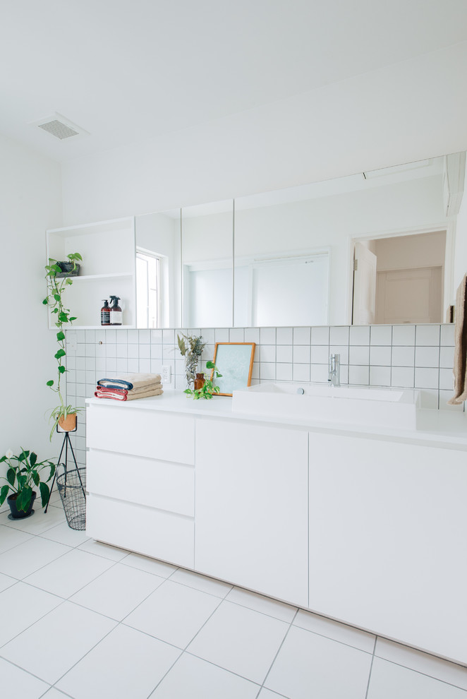 Design ideas for a scandinavian cloakroom in Other with flat-panel cabinets, white cabinets, white tiles, porcelain tiles, white walls, porcelain flooring, a vessel sink, white floors and white worktops.