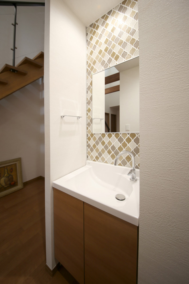 Exemple d'un WC et toilettes moderne en bois clair avec un placard à porte affleurante, un carrelage marron, mosaïque, un mur blanc, un lavabo intégré, un sol multicolore et un plan de toilette marron.