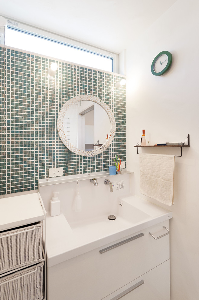 На фото: туалет с плоскими фасадами, белыми фасадами, синей плиткой, плиткой мозаикой, белыми стенами и белой столешницей