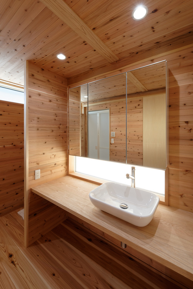 Exempel på ett modernt brun brunt toalett, med ett fristående handfat, träbänkskiva och mellanmörkt trägolv
