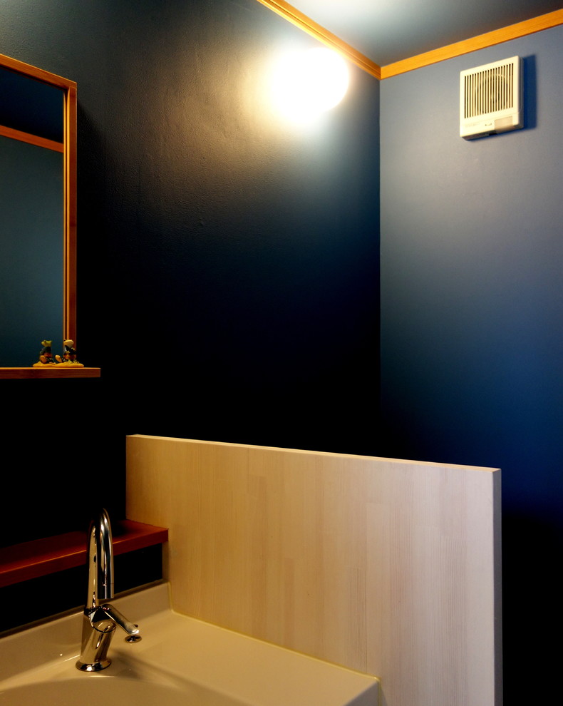 Foto di un piccolo bagno di servizio scandinavo con ante a filo, ante in legno chiaro, WC monopezzo, piastrelle blu, pareti blu, pavimento in vinile, lavabo integrato, top in superficie solida e pavimento beige