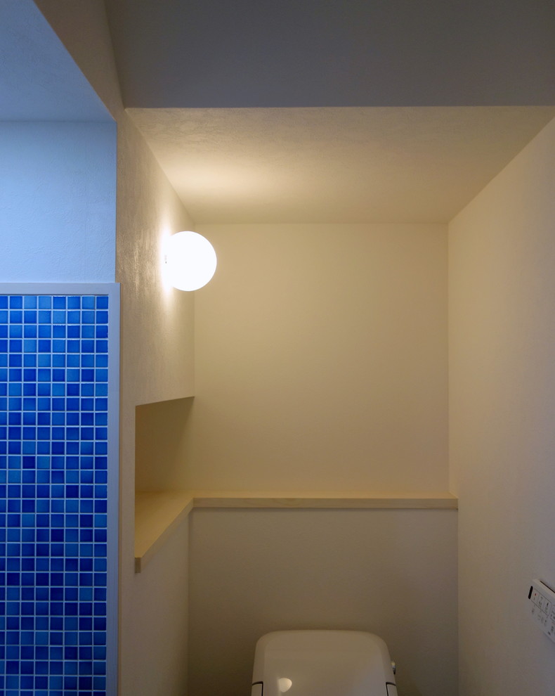 他の地域にある北欧スタイルのおしゃれなトイレ・洗面所 (一体型トイレ	、青いタイル、磁器タイル、白い壁、クッションフロア、ベージュの床) の写真