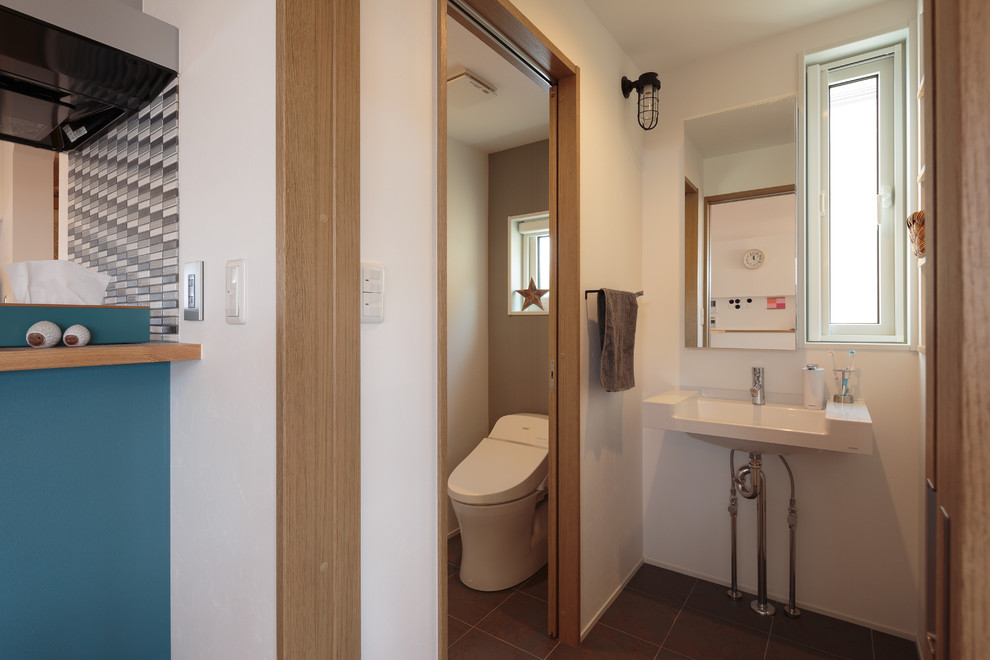 Inspiration för nordiska toaletter, med en vägghängd toalettstol, vita väggar, cementgolv, ett väggmonterat handfat och grått golv