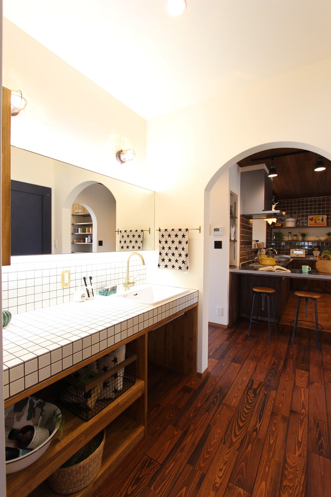 Retro Gästetoilette mit weißer Wandfarbe, braunem Holzboden, Aufsatzwaschbecken und braunem Boden in Sonstige