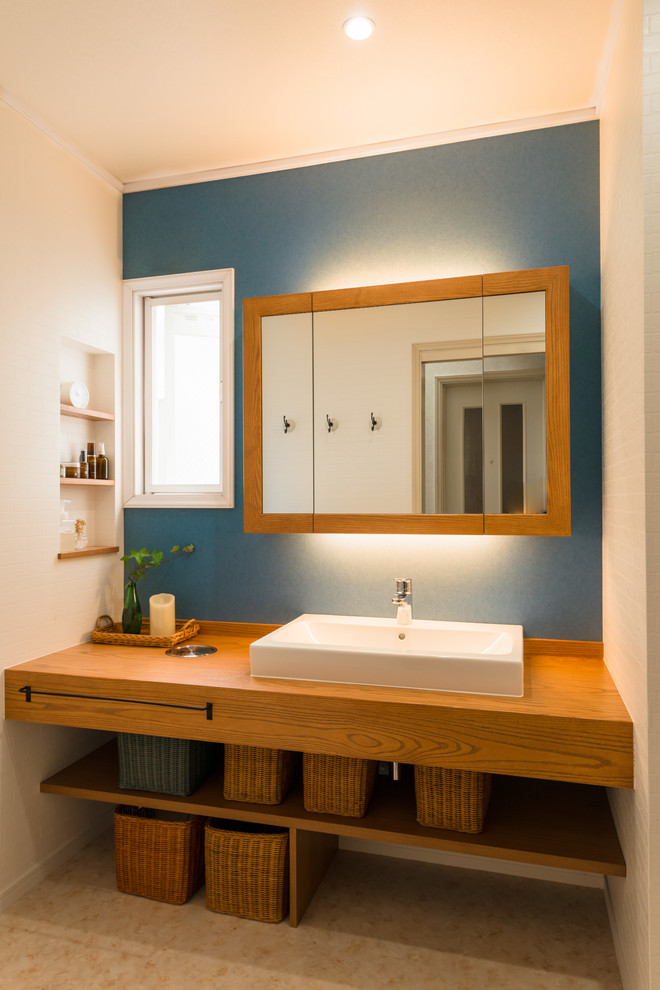 Inredning av ett medelhavsstil toalett, med blå väggar, ett fristående handfat, träbänkskiva och beiget golv