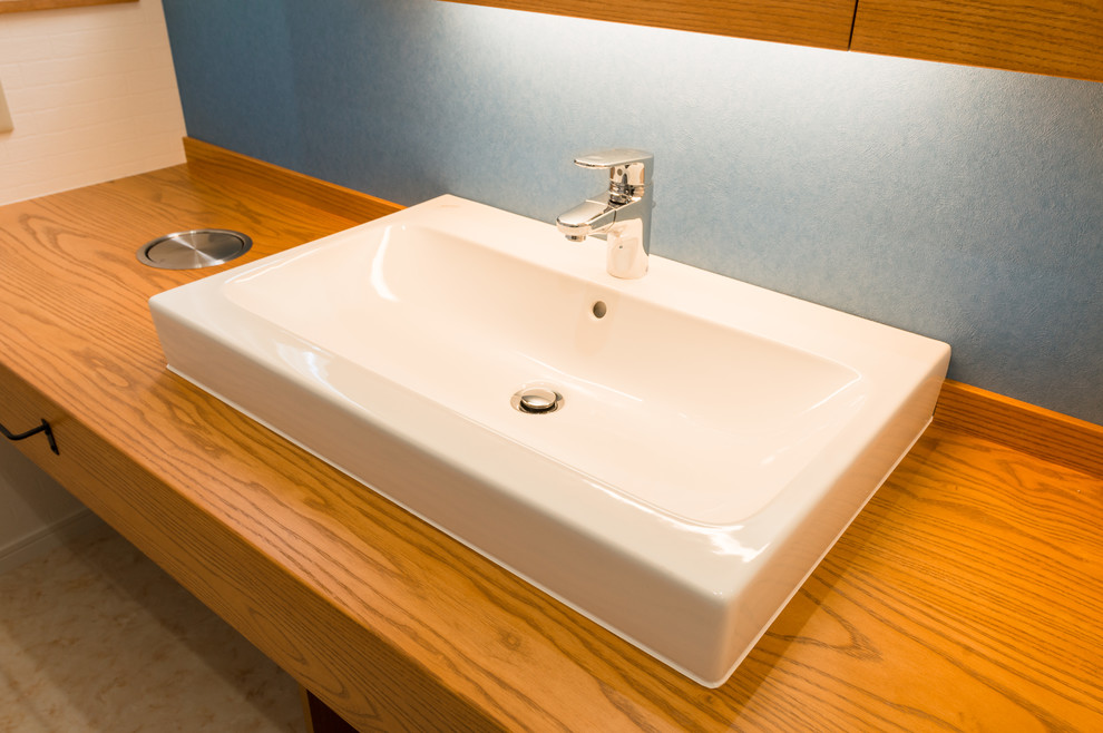 東京23区にある地中海スタイルのおしゃれなトイレ・洗面所 (青い壁、ベッセル式洗面器、木製洗面台、ベージュの床) の写真
