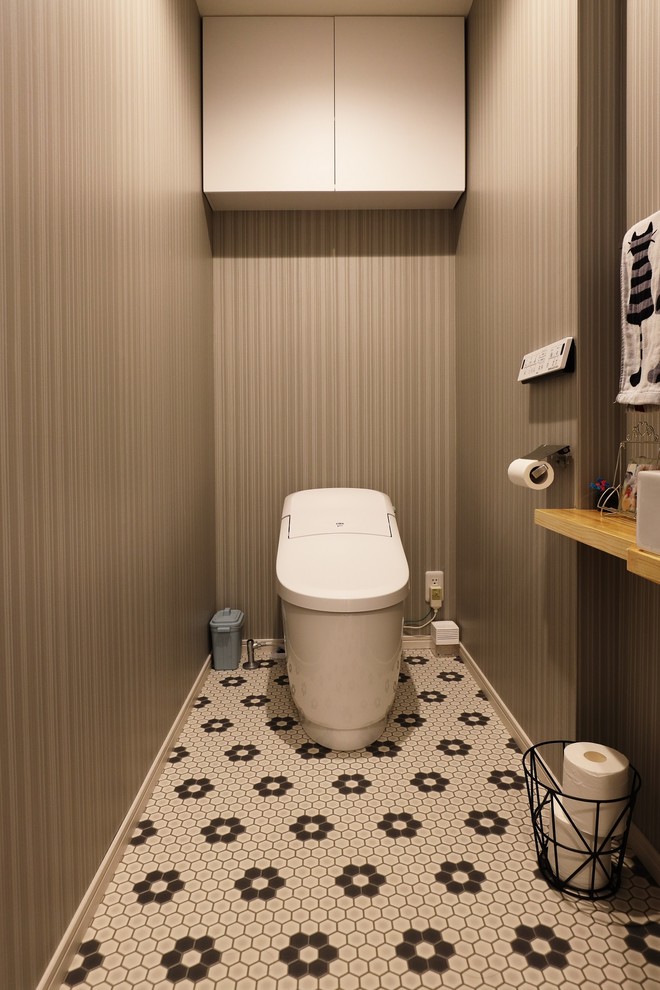 Idées déco pour un WC et toilettes moderne de taille moyenne avec un placard à porte plane, des portes de placard blanches, WC à poser, un mur gris, un sol en vinyl, une vasque, un plan de toilette en bois, un sol multicolore et un plan de toilette blanc.