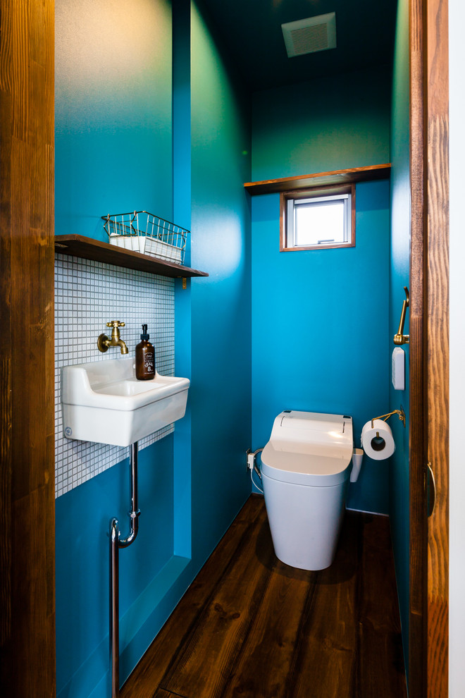 Photo of a small contemporary cloakroom in Other with brown cabinets, a one-piece toilet, white tiles, mosaic tiles, blue walls, dark hardwood flooring and brown floors.