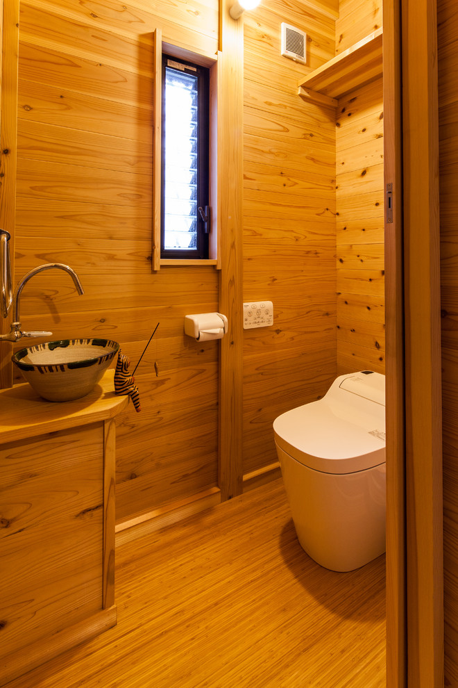 Cette photo montre un WC et toilettes asiatique en bois brun avec un placard à porte plane, un mur marron, un sol en bois brun, une vasque, un plan de toilette en bois, un sol marron et un plan de toilette marron.