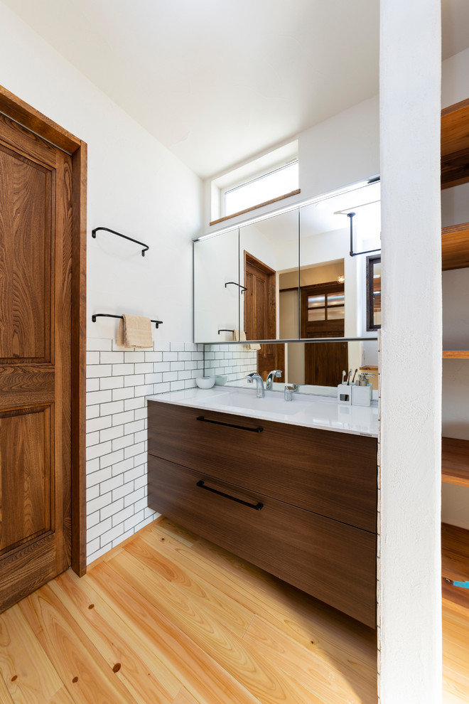 Immagine di un bagno di servizio industriale con piastrelle bianche, pareti bianche, pavimento in legno massello medio e pavimento multicolore