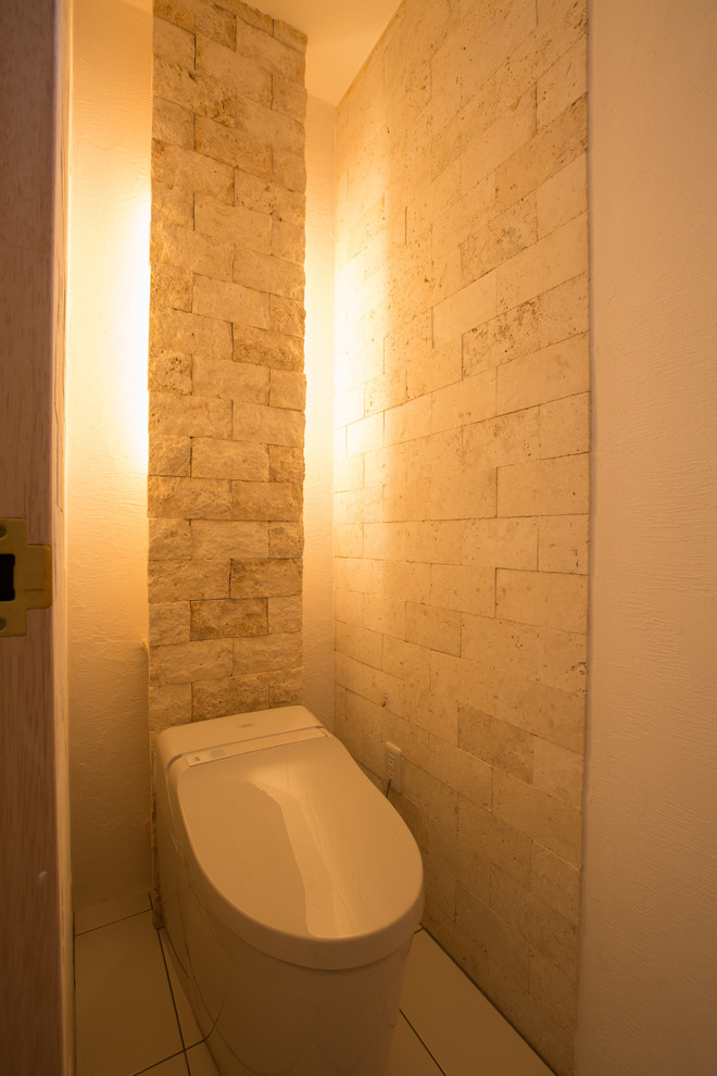 Свежая идея для дизайна: туалет среднего размера в стиле кантри с унитазом-моноблоком, бежевой плиткой, плиткой из известняка, белыми стенами и полом из керамогранита - отличное фото интерьера