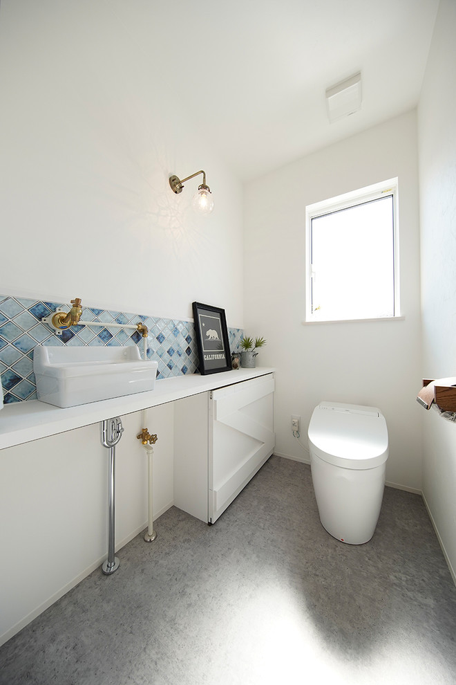 Immagine di un bagno di servizio nordico con pareti bianche, lavabo a bacinella e pavimento grigio