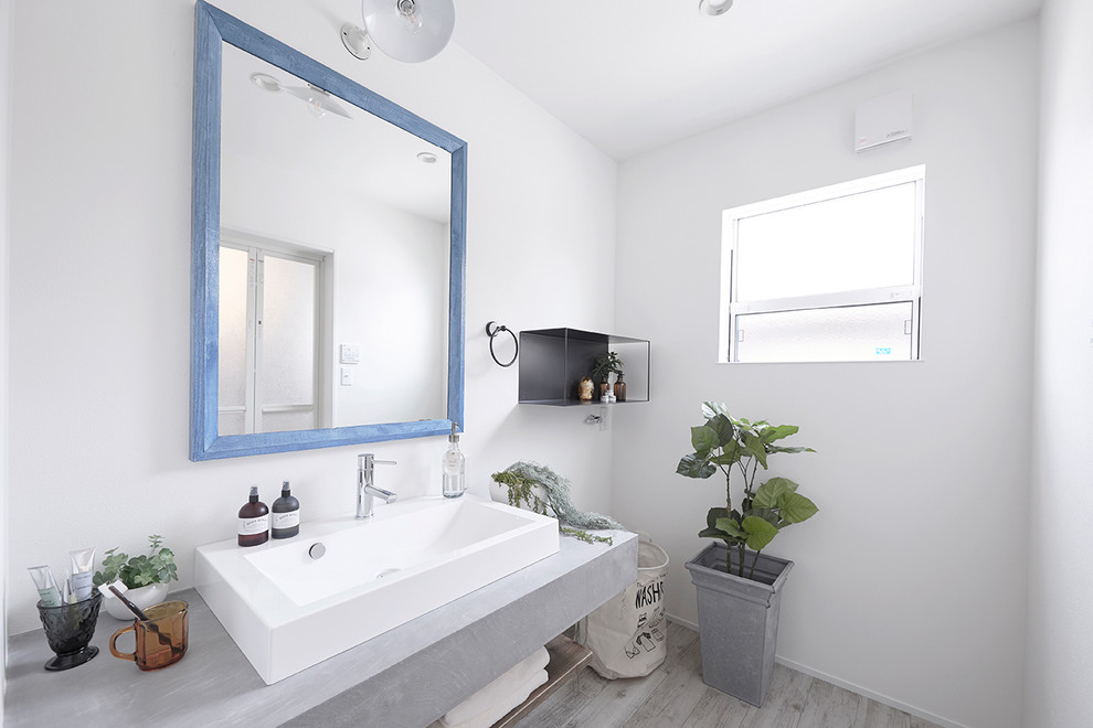 На фото: туалет в морском стиле с белыми стенами, деревянным полом, настольной раковиной и серым полом